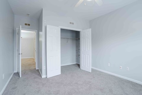 A room with a ceiling fan and two open doors.