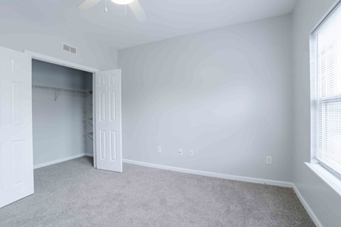 A room with a carpeted floor and a ceiling fan.