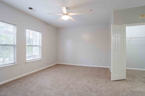 A room with a ceiling fan and carpeted floor.