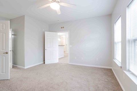A room with a ceiling fan and carpeted floor.