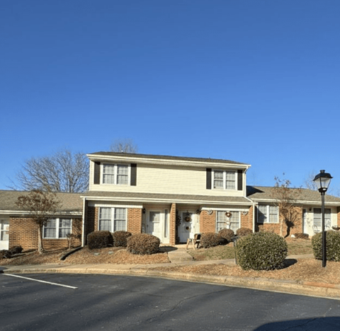 A residential building with a parking lot in front.