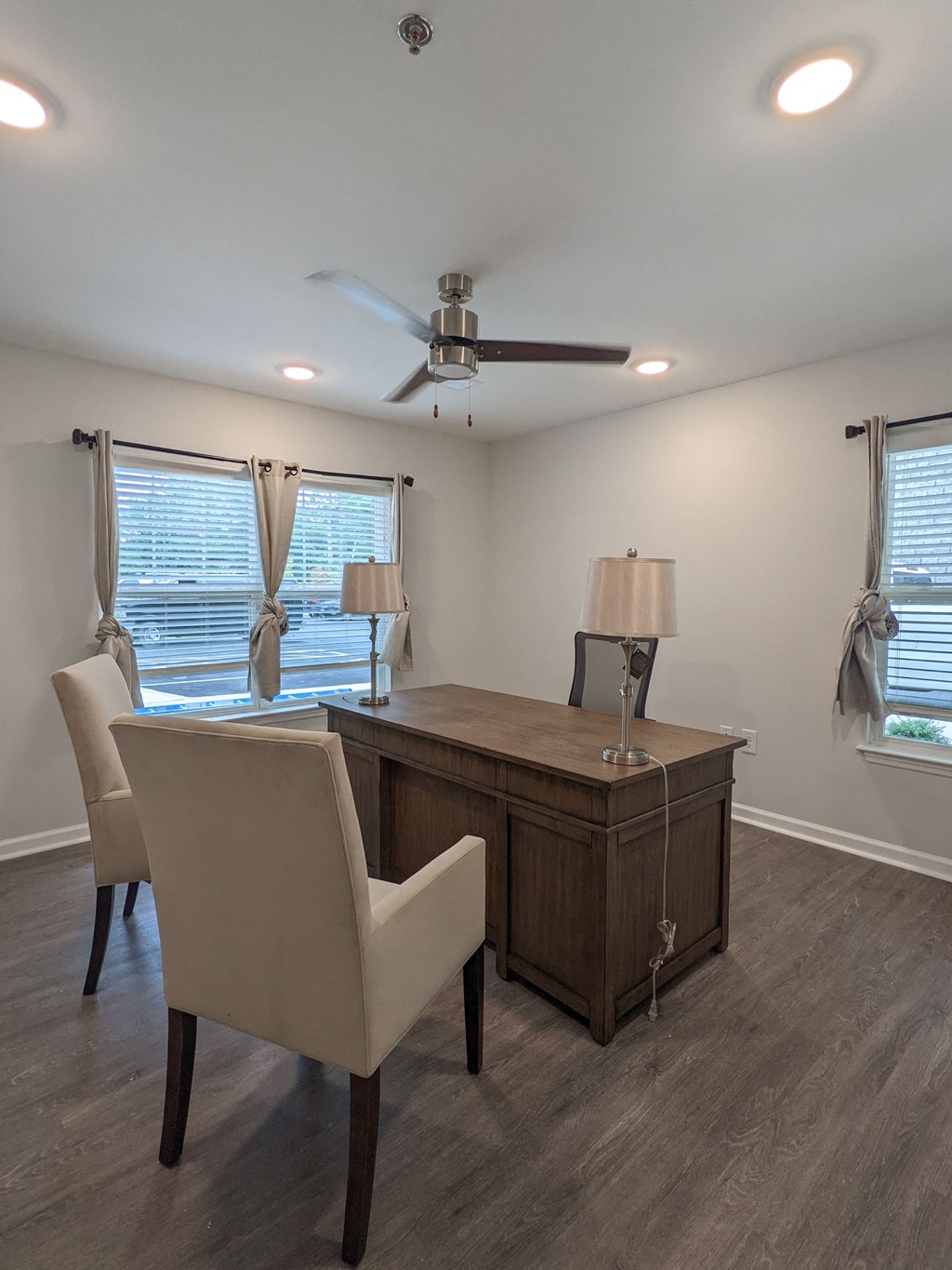 an office with a desk and chairs and a ceiling fan