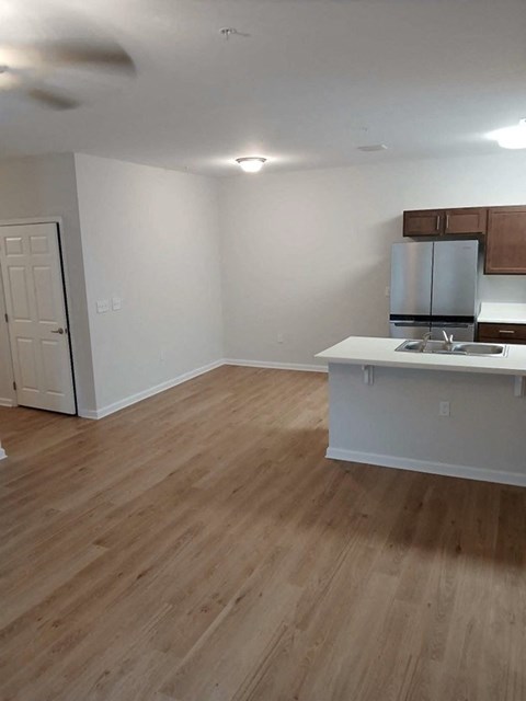 an empty living room and kitchen with wood floors
