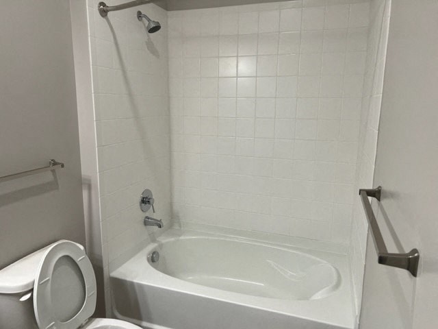 a white bathroom with a white tub and a toilet