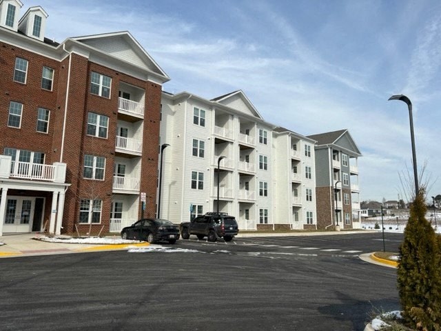 an apartment building with two cars parked in a parking lot
