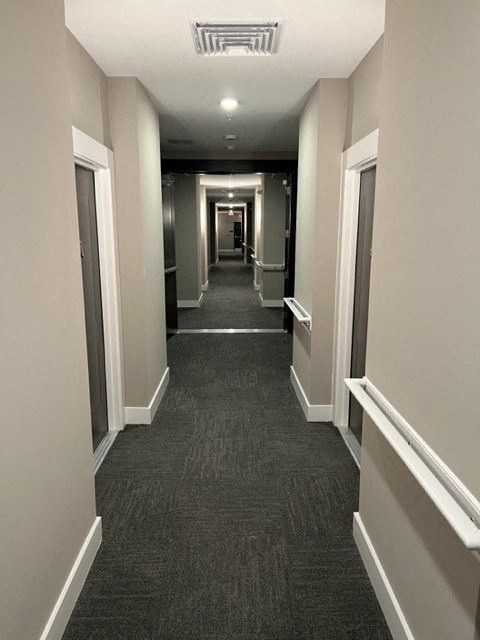 a long hallway with doors and a carpeted flooring