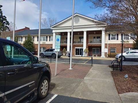 A black car is parked in a parking lot in front of a building.