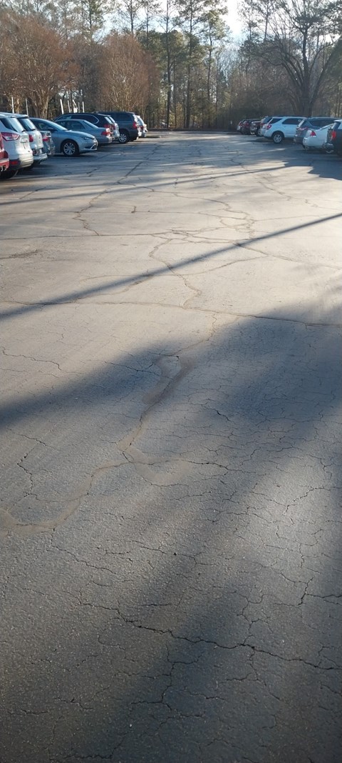 A parking lot with a few cars and trees in the background.