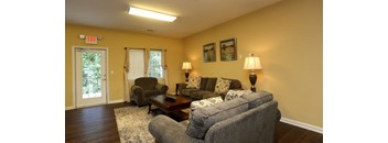 A living room with a grey couch, a brown coffee table, and a lamp at Robinson Park Apartments, Harrisonburg