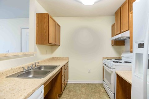 A kitchen with a white fridge, stove, and sink.