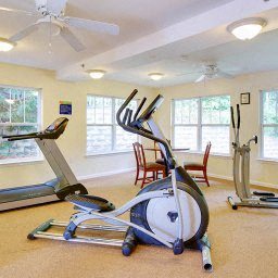 a gym with a exercise bike and a table and chairs