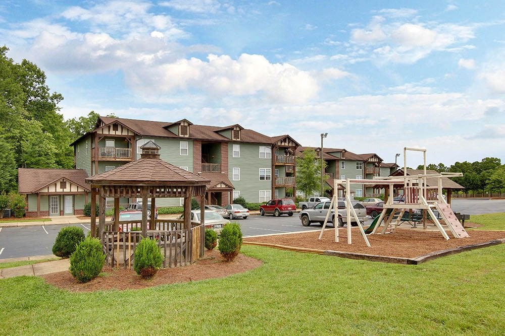 a playground with a swing set in front of an apartment building