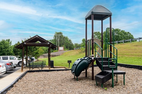 A playground with a green slide and a wooden structure.