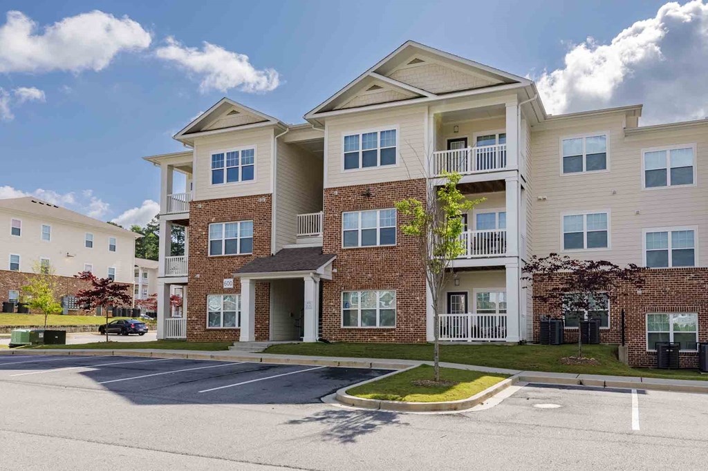 A large apartment complex with a parking lot in front.