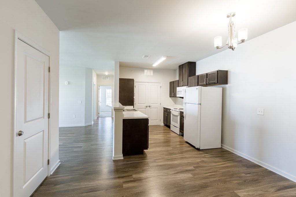 A kitchen with white appliances and a wooden floor.