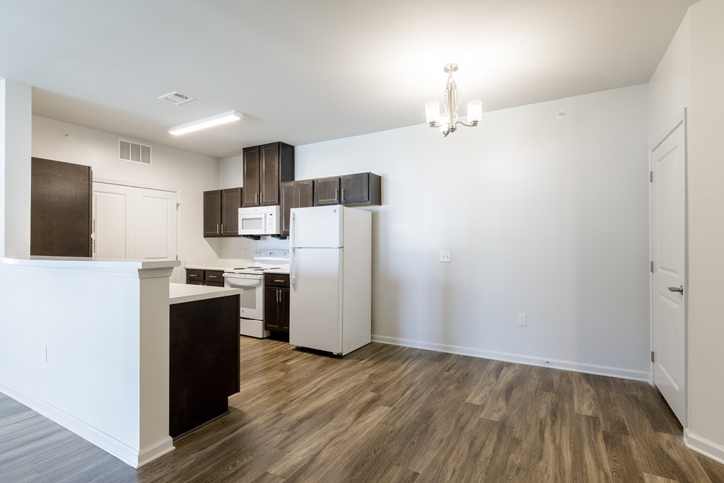 A kitchen with white appliances and wood floors.
