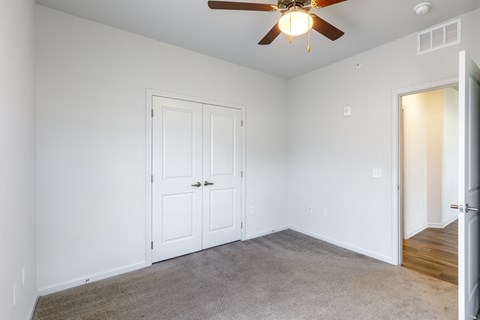 A room with a ceiling fan and two doors.