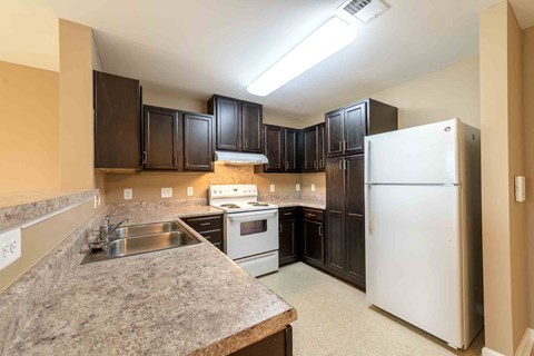 A kitchen with a white refrigerator and brown cabinets.