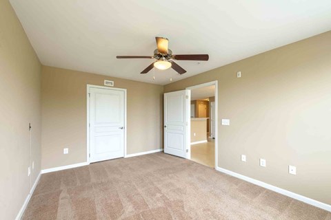 A room with a ceiling fan and carpeted floor.