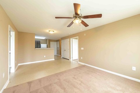 A spacious room with a ceiling fan and carpeted floor.