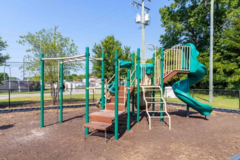 A playground with a green slide and a brown bench. at The Shire Apartments, Chesapeake, VA