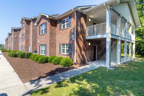 A red brick apartment building with a white balcony on the second floor. at The Shire Apartments, Chesapeake, Virginia
