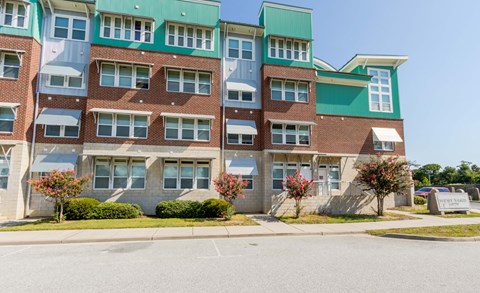 A multi-story building with a green roof and brick walls.