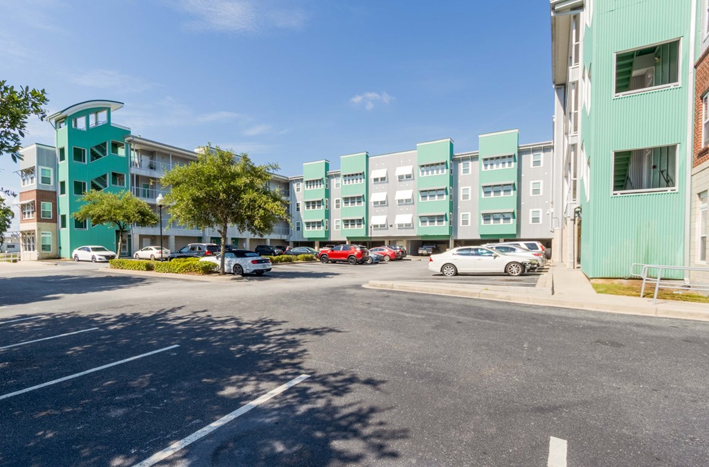 A parking lot with cars and a green building in the background.at West Yard Lofts, North Charlston South Carolina