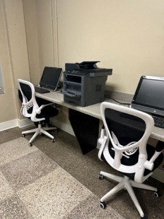 a desk with two chairs and two computers on it