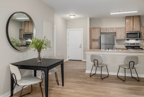 A kitchen with a black table and white chairs.
