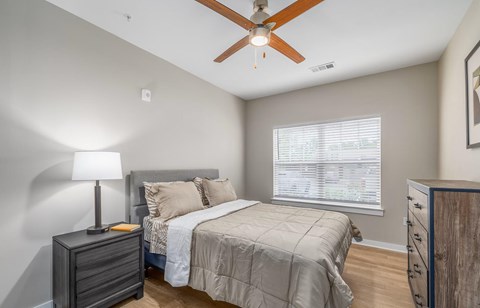 A bedroom with a bed, dresser, and ceiling fan.