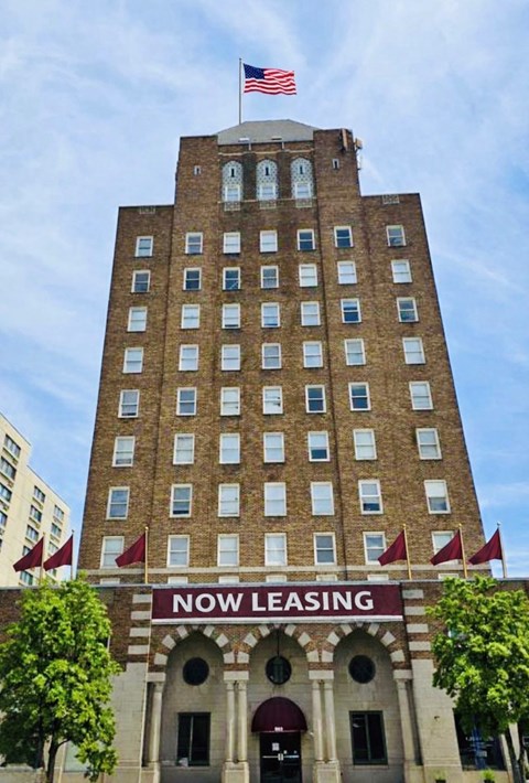 A tall building with a sign that says "Now Leasing" in front of it.