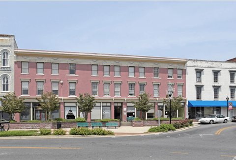 A street view of a row of buildings with a car parked in front of the first one.