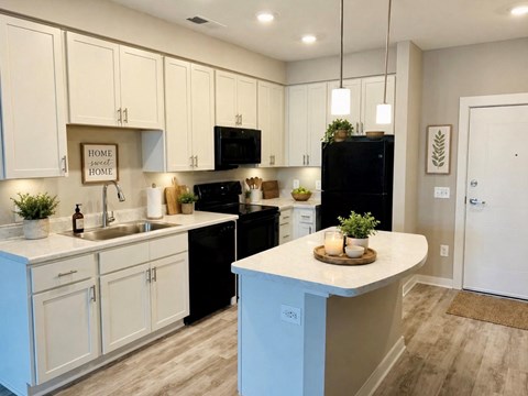 A kitchen with white cabinets and a black refrigerator.
