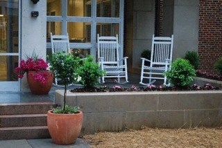 a front porch with two white rocking chairs and potted plants