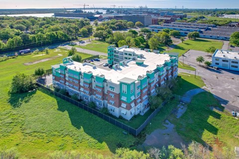 A large white and green building with a grassy area in front.