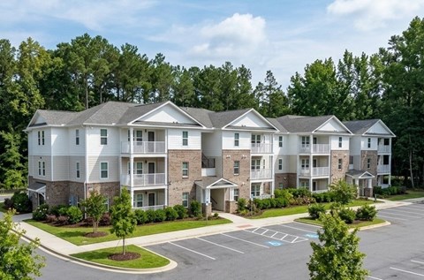 A large apartment complex with a parking lot in front.