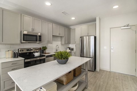 A modern kitchen with a white countertop and stainless steel appliances.