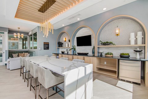 A modern kitchen with a long white table and chairs.
