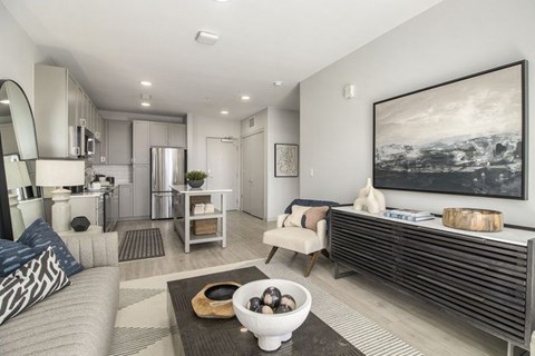 A modern living room with a grey sofa and a large painting on the wall.