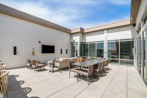 A patio with a table and chairs is surrounded by a white building.