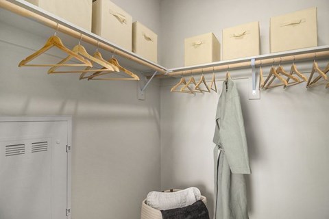 A closet with clothes hanging and boxes on shelves.