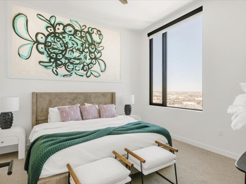 A bedroom with a large bed and a painting above it.