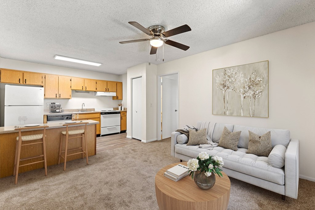 A living room with a couch, a dining table, and a ceiling fan.