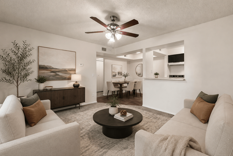 A living room with a white couch, a coffee table, and a ceiling fan.