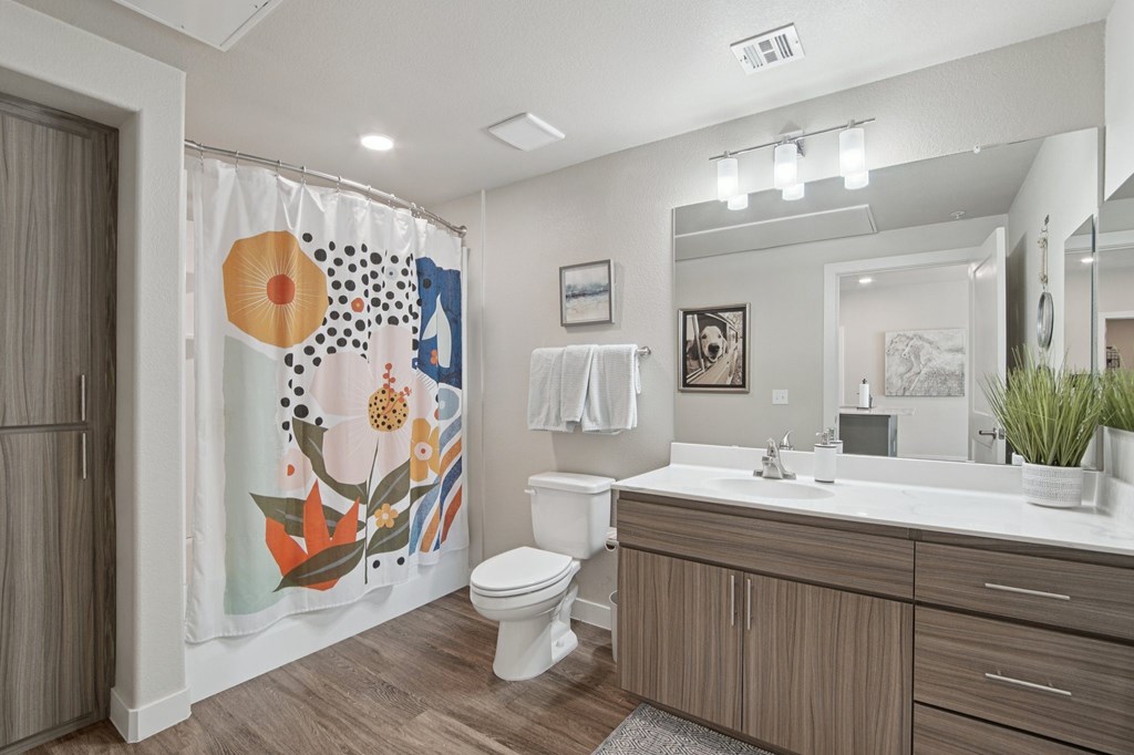 A bathroom with a toilet, sink, and a shower curtain with a floral pattern.