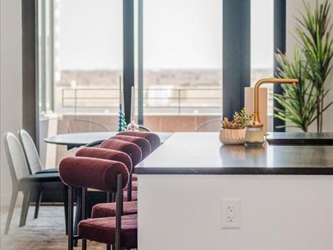 A kitchen with a table and chairs with a view of the outside.