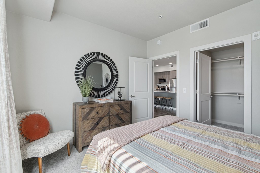 A bedroom with a bed, chair, and a dresser with a mirror.