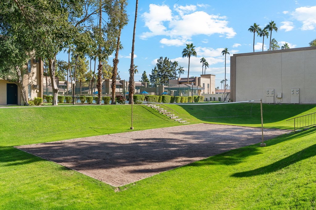 A large open area with a pathway and a green lawn.