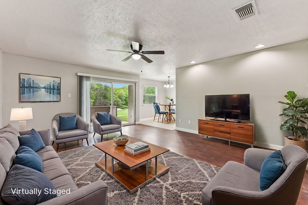 A living room with a grey couch, a coffee table, a television, and a ceiling fan.